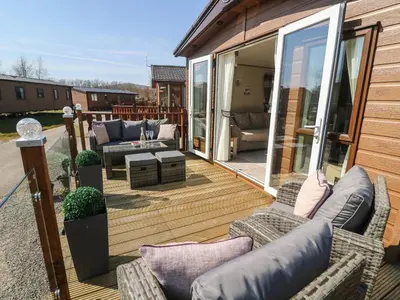 a patio with couches and chairs on a deck at Lancaster Lodge in Carnforth
