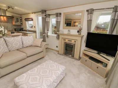 a living room with a couch and a tv and a fireplace at Lancaster Lodge in Carnforth