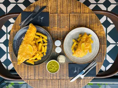 a table topped with two bowls of food and fries at The Pheasant Inn in Grange Over Sands
