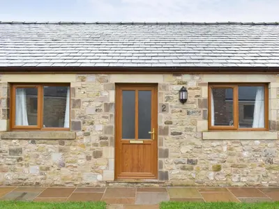 a stone house with a wooden door and windows at Two Dorchester Drive - Uk32036 in Inglewhite