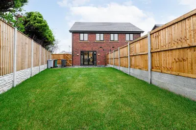 a backyard with a fence and a brick house at Tannery Place - 3 Bedrooms Parking Wi-Fi Garden in Freckleton