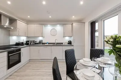 a kitchen with white cabinets and a glass table with chairs at Tannery House - 3 Bedrooms, Parking, Wi-Fi, Garden in Freckleton
