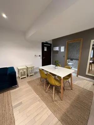 a living room with a table and yellow chairs at Beautiful City Centre Apartment in Liverpool