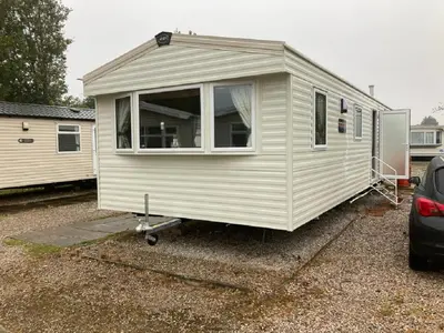 a white tiny house parked in a parking lot at Blackpool Static Caravan Marton Mere in Blackpool