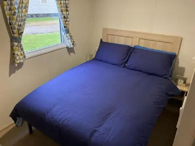 a blue bed in a bedroom with a window at Blackpool Static Caravan Marton Mere in Blackpool