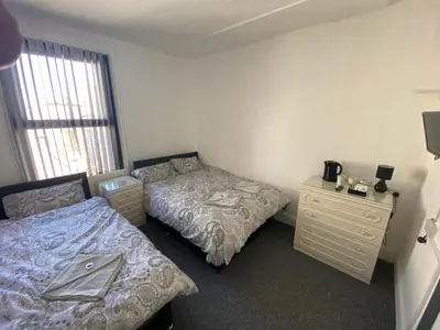 a bedroom with two beds and a dresser and a window at The Honley hotel in Blackpool