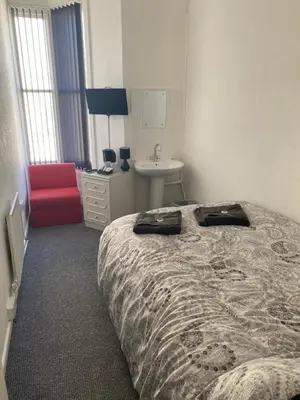a bedroom with a bed and a sink and a red chair at The Honley hotel in Blackpool