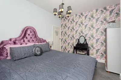a bedroom with a large bed with a purple headboard at Langan's Blackpool Holiday Let in Blackpool