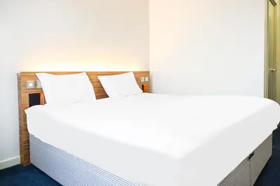 a bedroom with a large bed with white sheets at GO2 Lancaster Centre Hotel by OYO in Lancaster