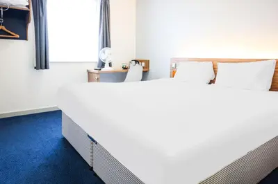 a bedroom with two beds and a blue carpet at GO2 Lancaster Centre Hotel by OYO in Lancaster