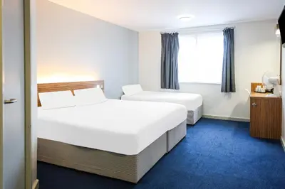 a hotel room with two beds and a window at GO2 Lancaster Centre Hotel by OYO in Lancaster