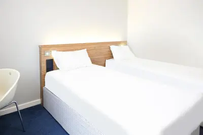 two beds in a room with a sink and a tub at GO2 Lancaster Centre Hotel by OYO in Lancaster