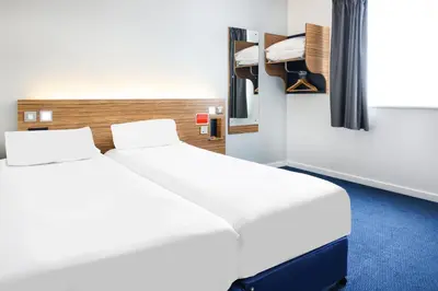 a bedroom with two beds and a mirror at GO2 Lancaster Centre Hotel by OYO in Lancaster