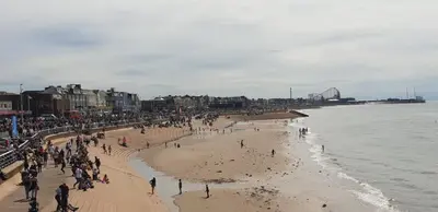 a group of people on a beach near the water at Coast Accommodation Station Road Apartments in Blackpool