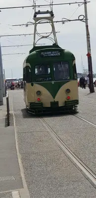 a green and white tram traveling down the tracks at Coast Accommodation Station Road Apartments in Blackpool