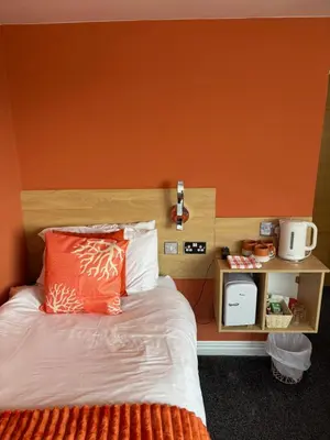 a bedroom with a bed with an orange wall at The Beaucliffe Hotel in Blackpool