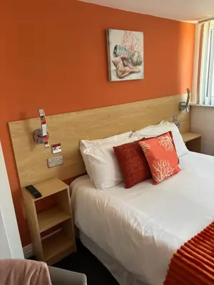a bedroom with a bed with an orange wall at The Beaucliffe Hotel in Blackpool