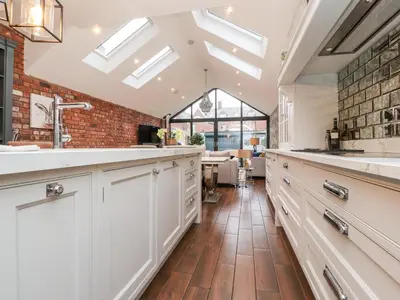 a kitchen with white cabinets and a brick wall at Westwood House in Lytham St Annes