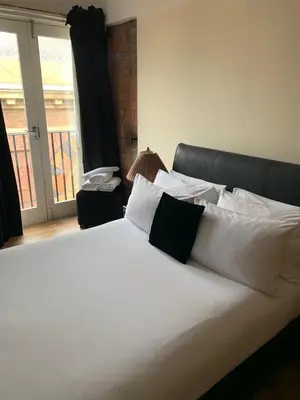 a large white bed with white pillows and a window at Contractor Bookers Liverpool City Centre in Liverpool