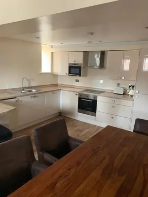 a kitchen with a wooden table and chairs and a kitchen with white cabinets at Contractor Bookers Liverpool City Centre in Liverpool