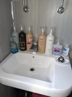 a bathroom sink with a bunch of bottles on it at Levens Terrace, Barrow Spa Therapy in Barrow in Furness