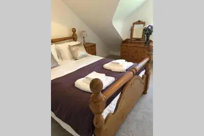 a bedroom with a large bed with a wooden frame at Dove Nest Cottage Blackpool Lytham St Annes in Lytham St Annes