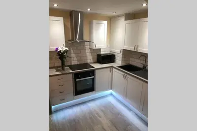 a kitchen with white cabinets and black counter tops at Dove Nest Cottage Blackpool Lytham St Annes in Lytham St Annes