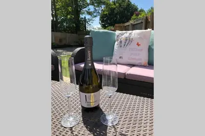 a bottle of wine and two wine glasses on a table at Dove Nest Cottage Blackpool Lytham St Annes in Lytham St Annes
