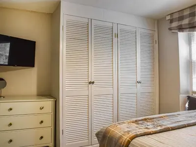 a bedroom with white closets and a bed at Beeswax Cottage in Dalton in Furness