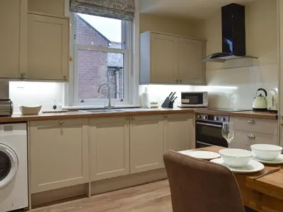 a kitchen with white cabinets and a table and a window at Beachcomber Corner in Lytham St Annes
