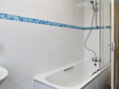 a white bathroom with a tub and a sink at Beachcomber Corner in Lytham St Annes