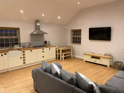 a living room with a couch and a kitchen at Pointer Cottage in Preesall
