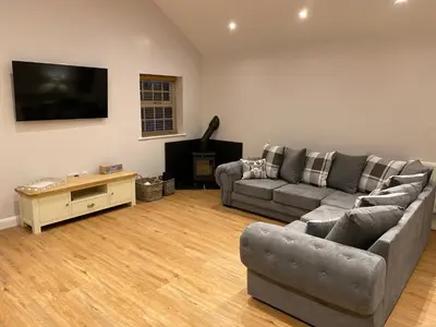 a living room with two couches and a flat screen tv at Pointer Cottage in Preesall