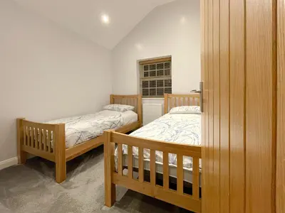 a bedroom with two beds and a window at Pointer Cottage in Preesall