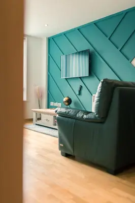 a living room with a couch and a blue wall at Sidemersey Livings- Convenient and Central 2-Bedroom Haven in L1, Secured Parking in Liverpool