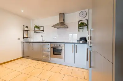 a kitchen with stainless steel appliances and a tile floor at Sidemersey Livings- Convenient and Central 2-Bedroom Haven in L1, Secured Parking in Liverpool