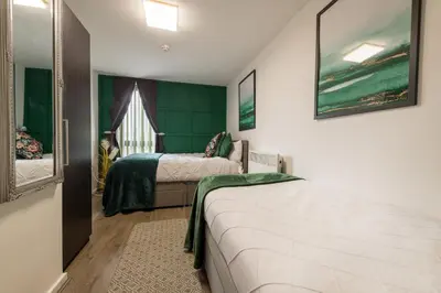 a bedroom with two beds and a green wall at Sidemersey Livings- Convenient and Central 2-Bedroom Haven in L1, Secured Parking in Liverpool
