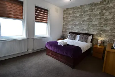 a bedroom with a bed with a purple blanket and two windows at Hotel 33 in Blackpool