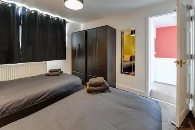 a bedroom with two beds and a cabinet and a window at 3 BR Home l Free Parking l 5 Guests l Garden l Long Stays l in Wigan