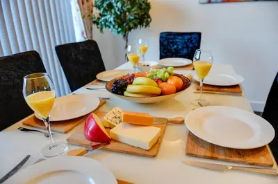 a table with a plate of food and glasses of wine at 3 BR Home l Free Parking l 5 Guests l Garden l Long Stays l in Wigan