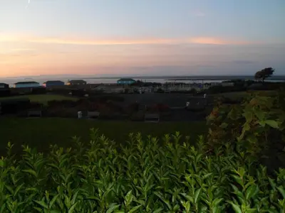 a view of a field with the sunset in the background at Wavecrest Lodge in Fleetwood