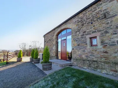 a stone house with a red door and some plants at Hill Brook Barn in Clitheroe