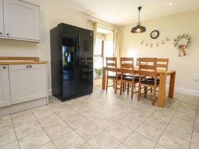 a kitchen with a black refrigerator and a table and chairs at Hill Brook Barn in Clitheroe