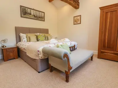 a bedroom with a bed and a wooden cabinet at Hill Brook Barn in Clitheroe