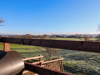 a wooden fence with a tree in a field at Hill Brook Barn in Clitheroe