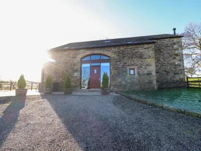 a stone house with a red door on a gravel driveway at Hill Brook Barn in Clitheroe