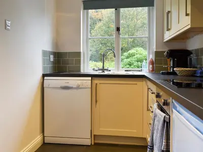 a kitchen with a sink and a dishwasher and a window at The Burrow in Haverthwaite