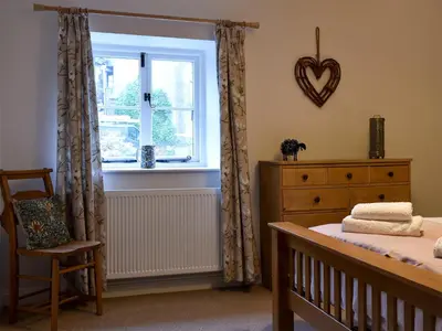a bedroom with a bed and a window and a chair at The Burrow in Haverthwaite