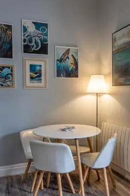 a table and chairs in a room with paintings at Beach Snug in Lytham St Annes