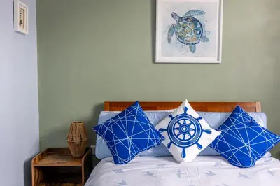 a bed with blue and white pillows on it at Beach Snug in Lytham St Annes